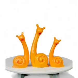 Bright Orange Ceramic Snail Family – Modern Art Figurine Set Each snail is handmade by skilled artisans, featuring a modern, minimalist shape that pairs beautifully with contemporary interiors. The bright orange hue and fluid design make them ideal for display on consoles, shelves, or tabletops — perfect for adding a touch of whimsy and personality to your décor. Whether styled together as a family set or separately in different spaces, these ceramic pieces are sure to spark joy and conversation. Features: Set of 3 handcrafted ceramic snail figurines Glossy orange finish with smooth detailing Perfect for modern or playful home décor Ideal for gifting or adding a pop of color to interiors Handcrafted by DNF Ceramics artisans