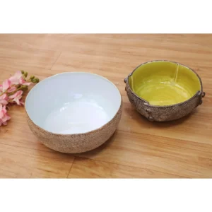 The Terra Glaze Textured Bowls – Set of 2 celebrate contrast through material and color. Each bowl is hand-thrown with a richly textured, stone-like exterior that highlights the natural clay body, paired with a smooth, glossy glazed interior. One bowl features a soft ivory white interior for timeless elegance, while the other is finished in a vibrant sunlit yellow glaze that adds warmth and character to the table. Subtle glaze variations and tactile surface detailing emphasize the handmade nature of each piece. Ideal for serving salads, soups, snacks, or desserts, these bowls work beautifully in modern homes, boutique restaurants, and curated hospitality spaces. Their bold yet refined aesthetic makes them equally suitable as functional serveware or statement décor pieces.